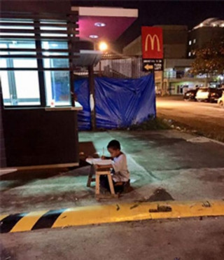 Cậu bé vô gia cư dùng ánh sáng lọt từ nhà hàng để học bài